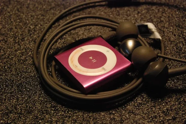 Close-up of a pink MP3 player with earphones coiled around it on a textured surface.