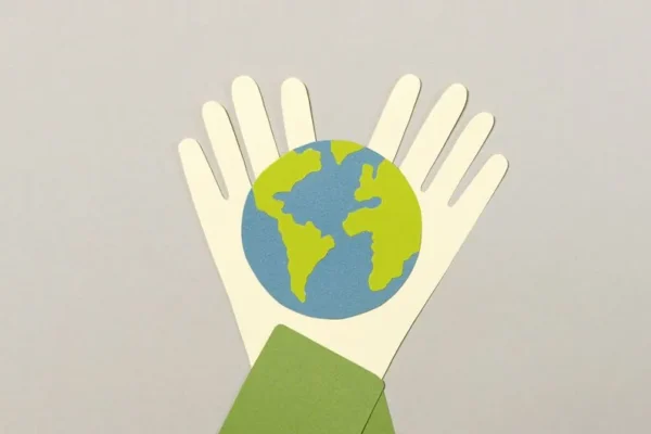 Creative paper cutout art representing Earth held by hands, symbolizes environmental protection.