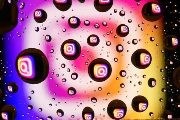 Vibrant water droplets on a colorful background reflecting Instagram logos, showcasing abstract digital creativity.